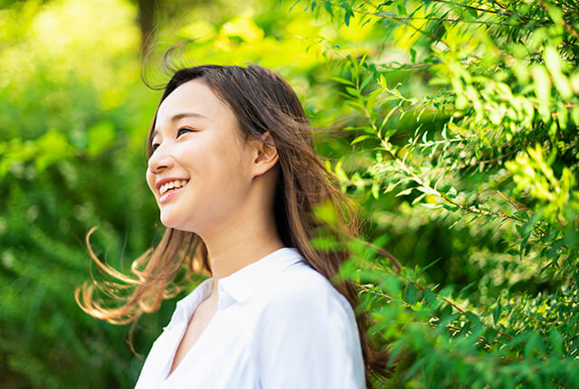 自然に囲まれる笑顔の女性